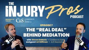 Two men with microphones sit at a table discussing mediation for the Injury Pros Podcast, Episode 7, titled “The ‘Real Deal’ Behind Mediation.”.