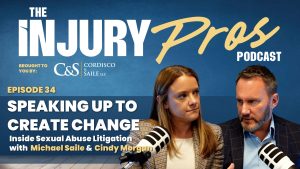 Two podcast hosts, a woman and a man, sit with microphones discussing Episode 34 of "The Injury Pros Podcast" about speaking up in sexual abuse litigation.
