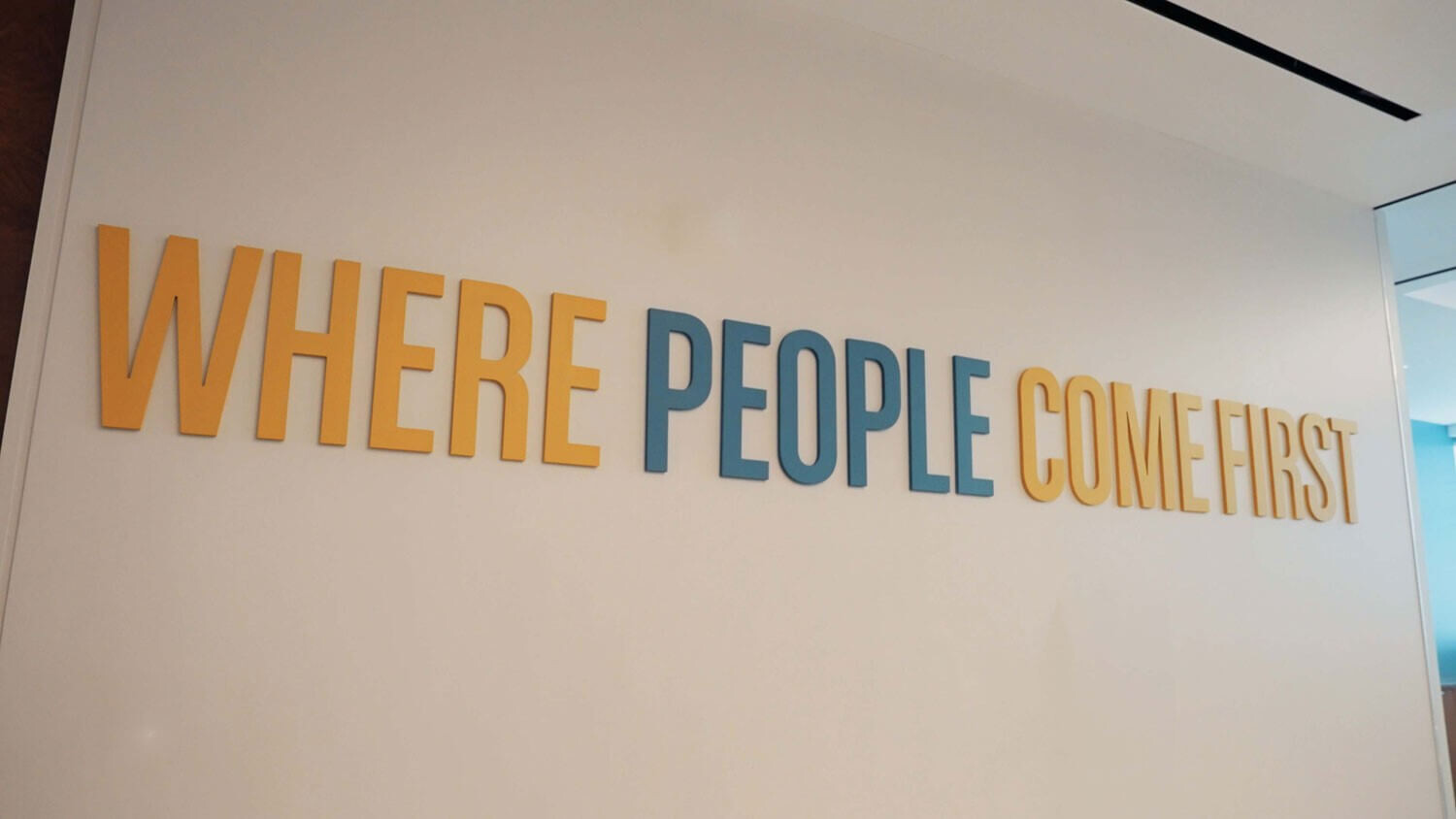Wall with the phrase "WHERE PEOPLE COME FIRST" in large yellow and blue letters.